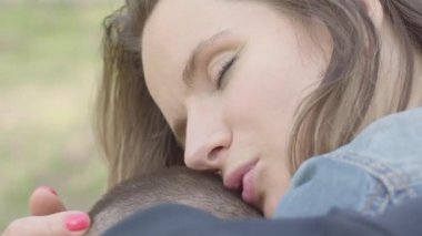 Yakın portre sevimli anne sarılmak genç oğlu ve onu öpmek. Anneler sevgi ve bakım