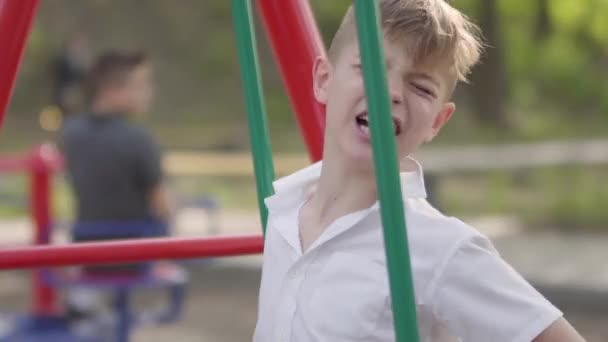Mladý chlapec pláče u houpačky, kluk se zranil. Venkovní rekreace. — Stock video
