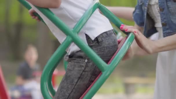 Linda madre empujando riendo dos hijos en swing en un parque. Mamá y los niños están descansando activamente al aire libre. Relación madre e hijos. recreación al aire libre . — Vídeo de stock