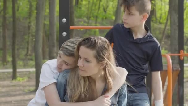 Mor till många barn i parken med sina söner. Pojkarna springer runt, en av dem kramar kvinnan. Stor vänlig kärleksfull familj. Fritid utomhus, moderskapet konceptet. Friluftsliv. — Stockvideo