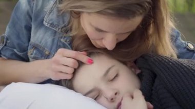 Sevimli çocuk annelerin elinde uyku, kadın parkta çocuğunun saçlarını okşar. Boş zaman, annelik, dost aile