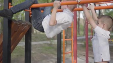 İki oyuncu ikizler kardeşler eğitim ve bahar parkı oyun alanında yatay barlarda oynuyor