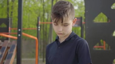 Çocuk bahçesinde eli bandajlı genç bir çocuk. Çocuk oynamak istiyor ama yaralı.