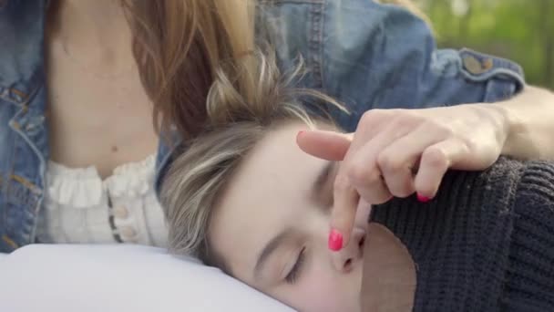 Retrato niño bonito durmiendo en las manos de las madres, la mujer acaricia el pelo de su hijo en el parque. Ocio al aire libre, maternidad, familia amable — Vídeos de Stock