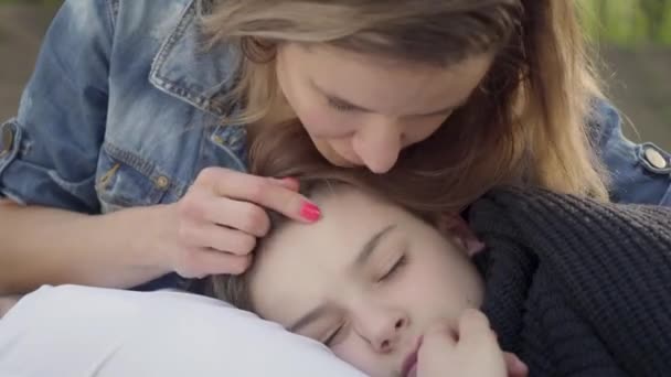 Χαριτωμένο αγόρι που κοιμάται στα χέρια της μητέρας, η γυναίκα χαϊδεύει τα μαλλιά του παιδιού της στο πάρκο. Αναψυχή σε εξωτερικούς χώρους, μητρότητα, φιλική οικογένεια — Αρχείο Βίντεο