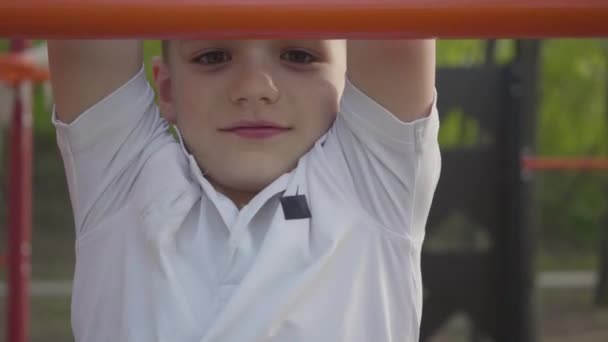 Kleine knappe jongen klimmen Childrens stappen op de speeltuin close-up. Actieve levensstijl, zorgeloze kindertijd, schattig kind buitenshuis spelen — Stockvideo