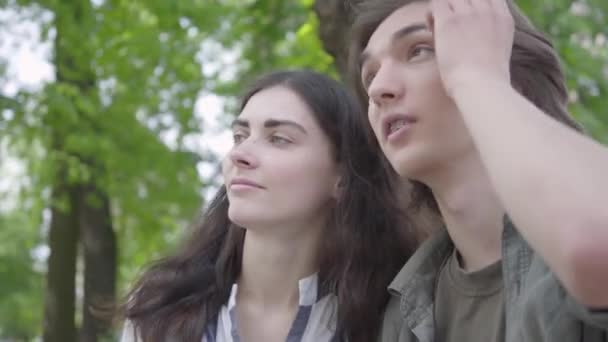 Portrait joli jeune couple amoureux portant des vêtements décontractés assis sur le banc parlant et se tenant la main. Joyeux garçon et fille qui passent du temps ensemble dans le parc. Loisirs en plein air — Video