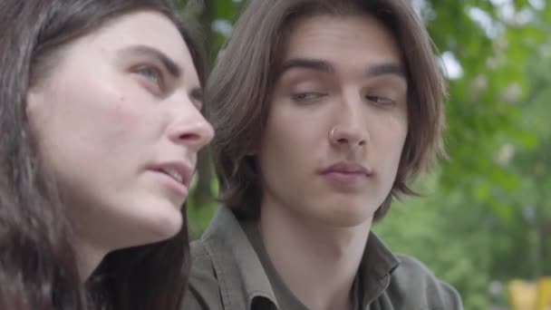 Portrait adorable jeune couple en vêtements décontractés passer du temps ensemble dans le parc, avoir un rendez-vous. Le mec plaisante et la fille rit joyeusement. Loisirs en plein air, heure d'été. Caméra en mouvement — Video