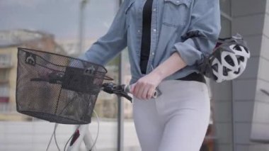 Tanınmayan genç spor beyaz kot pantolon ile ince çekici sarışın kadın şehirde vitrinler yakınında bisiklet lider. Sıcak bayan açık havada vakit geçiriyor, aktif yaşam tarzı. Kamera yukarı hareket ediyor