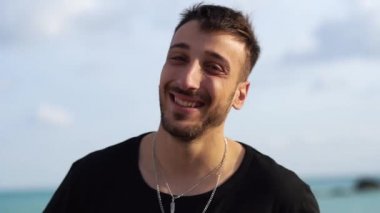 Genç yakışıklı bir adam mutlu bir şekilde iyi ve şaşırtıcı bir haberi fark ediyor ya da harika bir fikri var, sakala dokunurken şaşkınlıkla gülümsüyor..
