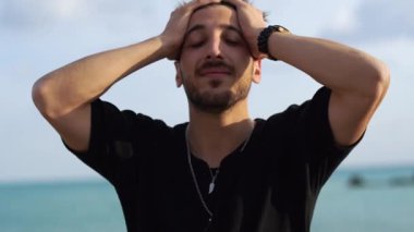 Genç sakallı adam hayret verici bir ifadeyle gülümserken güzel siyah saçlarına elleriyle dokunuyor..