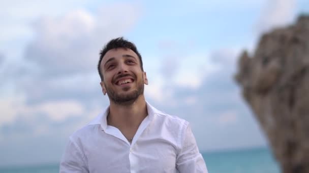 Молодой красивый мужчина счастливо улыбается с удивленным выражением лица и машет рукой. Кипр. Пафос — стоковое видео