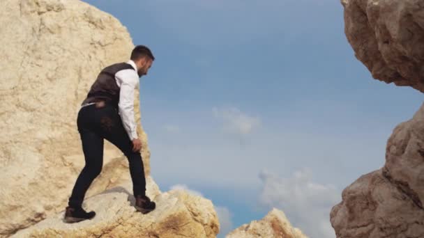 Jovem homem elegante subir nas montanhas com muito cuidado com os seus passos. Chipre. Paphos — Vídeo de Stock