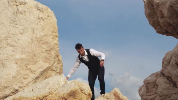 Młody stylowy mężczyzna spacerujący po skale na świeżym powietrzu. Udany wolny facet stojący na wielkim kamieniu. Cypr. Pafos — Wideo stockowe