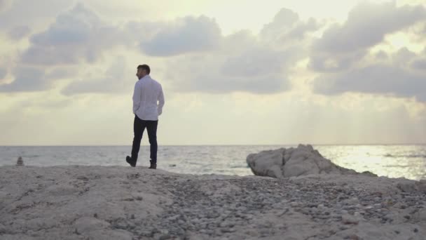 Junger Mann, der am Strand spazieren geht und die herrliche Aussicht auf das Meer und das schöne Wetter genießt. Zypern. Paphos — Stockvideo