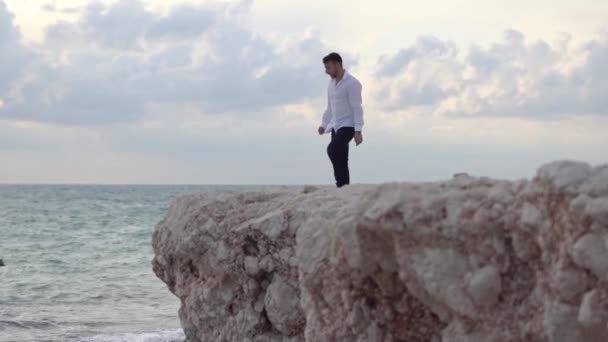 Young happy man sit on the high hill of rock and enjoying amazing view of seaside and beautiful weather. Cyprus. Paphos — стокове відео