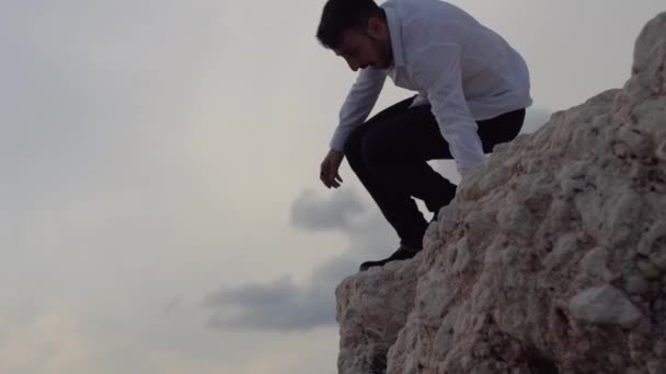 Mladý muž sedící na vysokém skalním kopci a užívající si nádherný výhled na moře. Šťastnej chlap řve a hvízdá. Yung Man věří v budoucnost a úspěch.. — Stock video