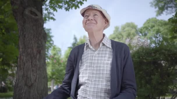 Портрет симпатичного старика, сидящего на скамейке в парке. Очаровательный зрелый дедушка отдыхает в солнечный теплый весенний день на открытом воздухе . — стоковое видео