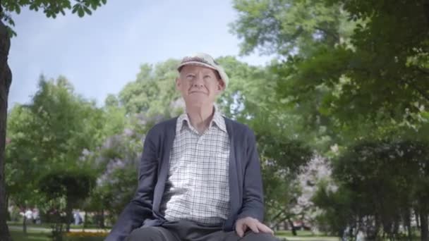 Porträt eines alten Mannes in einem wunderschönen Park. entzückender reifer Großvater, der sich an einem sonnigen warmen Frühlingstag im Freien ausruht. — Stockvideo