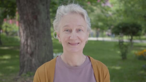 Diferentes emociones de anciana con pelo gris en el hermoso parque. Adorable abuela madura descansando en un soleado cálido día de primavera al aire libre . — Vídeos de Stock