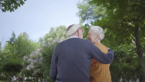 Portré érett pár szerelmes ül egy padon a parkban. Felnőtt nő és öregember együtt. Tender kapcsolat felnőtt pár szabadban. Hátulnézet. — Stock videók