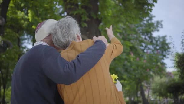 Porträt eines niedlichen, reifen verliebten Paares, das auf einer Bank im Park sitzt. erwachsene Frau und alter Mann zusammen. Zarte Beziehung liebenswertes Paar im Freien. zurück. — Stockvideo