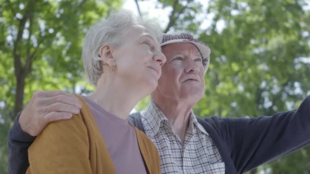 Retrato de um casal maduro apaixonado sentado em um banco no parque. Uma mulher adorável e um velho juntos. Tender relacionamento adulto casal ao ar livre . — Vídeo de Stock
