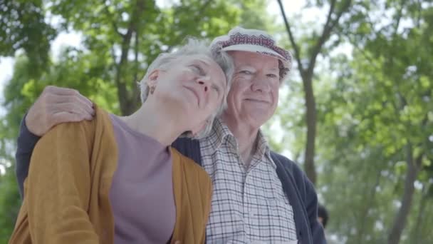 可爱的成熟夫妇在爱坐在公园的长凳上的肖像。可爱的女人和老人在一起。温柔关系 成人 夫妇 户外. — 图库视频影像