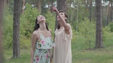 Gökyüzünde bakarak, aroung inanılmaz doğa ayakta kısa beyaz elbiseler iki güzel kadın portresi. Muhteşem bir manzara. Yavaş çekim.