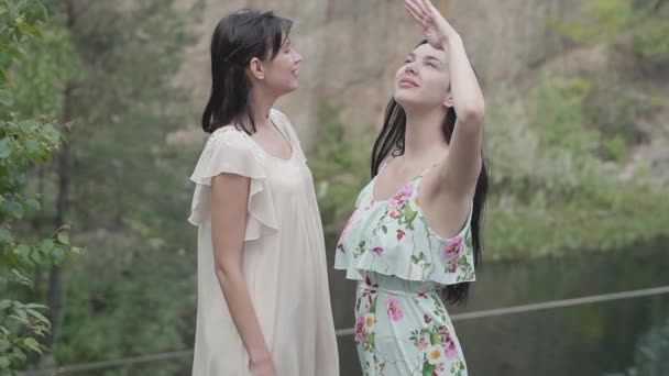 Duas mulheres bonitas em vestidos brancos curtos em pé aroung natureza incrível, olhando no céu. Vista espectacular. Movimento lento . — Vídeo de Stock