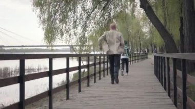 Küçük çocuk nehir kenarındaki tahta köprüde büyükbabasından kaçıyor. Yaşlı adam yorgundu ve nefes almak için durdu. Açık havada oynayan aile