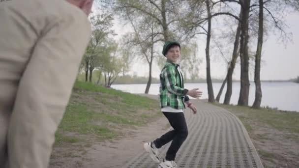 Jongetje loopt van zijn grootvader in het Park, hij wil naar de rivier gaan. De oude man kan de jongen niet volgen, hij is moe en gestopt om zijn adem te vangen. Familie spelen buitenshuis — Stockvideo