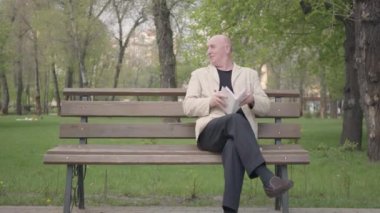 Parkta bankta oturup kitap okuyan kel olgun adam. Küçük bir çocuk ona gelir, büyükbaba çocuğun elini alır ve çekip giderler. Açık havada boş zaman, yaz eğlencesi