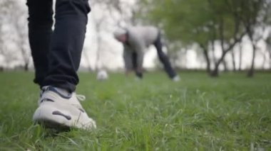 Torun topa vuruyor ve dedesi golü kaçırıyor. Mutlu sevimli çocuk futbol topu için yürürken ön planda atlama. Dışarıda eğlenen aile, aktif yaşam tarzı