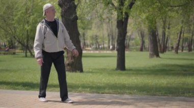 Parkta damalı gömlek sevimli çocuk paten, dedesi onu yakalamak ve sarılma. Açık havada aktif boş zaman. Büyükbabasıyla eğlenen çocuk. Yaşlı adam torunuyla vakit geçiriyor