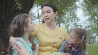 Portre sevimli olgun mutlu büyükanne büyük yeşil ağacın yakınındaki güzel parkta otururken onun torunları öğretim. Mutlu bir aile dışarıda vakit geçirir. Nesiller kavramı.