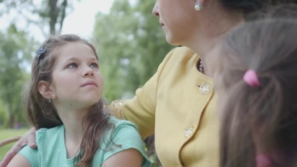 Portret schattig volwassen gelukkig grootmoeder onderwijs haar kleindochters terwijl zittend in het prachtige park in de buurt van Big Greentree. Gelukkige familie tijd buitenshuis doorbrengen. Concept van generaties — Stockvideo