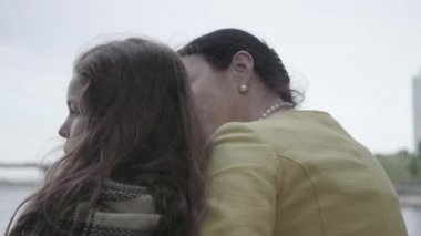 Nehir kıyısında oturan zarif olgun bir kadının arka görünümü, onun sevimli torunu ile sarılma. Mutlu bir aile dışarıda vakit geçirir. Doğayla bağlantı. Close