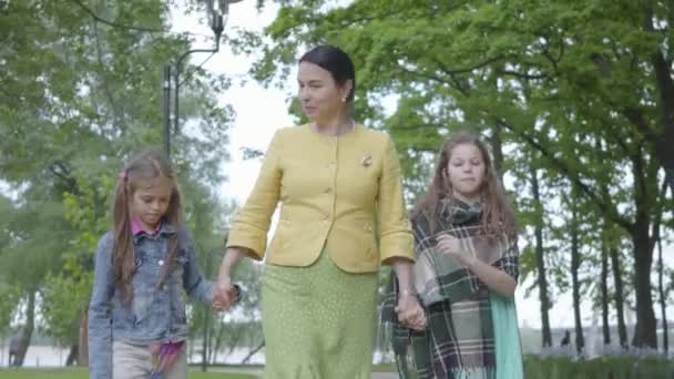 Porträtt mogen mormor går i den vackra gröna parken med två söta barnbarn hålla händerna med dem och springa. Begreppet generationer. Fritid tillsammans. — Stockvideo