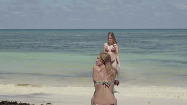 Seychelles. L'île Praslin. Deux filles minces en maillot de bain se reposent sur la plage avec une eau spectaculaire bleue incroyable et une femme marche vers la mer pour nager. Tropical île vacances de luxe . — Video