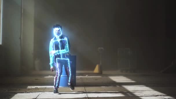 Zářící neonové linie moderního barevného osvětlení. Profesionální mladý hip-hop mužský tanečník ve sportu nosí tanec v temné opuštěné budově před modrým plynovým sudem. Současné. Hip hop — Stock video