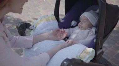 Mutlu anne arabada bebek ile konuşan ve gülümseyerek ve güzel bir bahar gününde ona bakmak