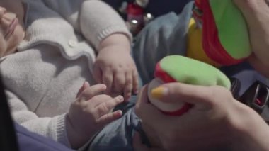 Parkta bebek arabasında yatan bebeğiyle oynayan kızıl saçlı güzel kadının yakın çekim görüntüsü. Bayan, güneşli bir günün tadını çocuğuyla dışarıda geçiriyor. Çocuklu genç bir anne. Mutlu aile