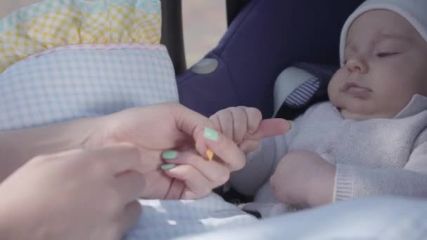 Joven madre feliz jugando y cuidando de su bebé lindo recién nacido en carruaje en un buen día de primavera — Vídeos de Stock
