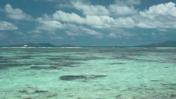 Сейшельские острова. Остров Праслин. Удивительный морской пейзаж с чистой голубой водой и небом. Одинокая яхта далеко в океане. Исландия далеко на горизонте. Туризм, путешествия — стоковое видео