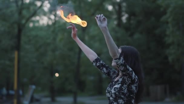 Grace hermosa chica realizando un espectáculo con llama de pie frente al bosque. Artista experto en fuegos artificiales que exhala un poderoso chorro de fuego. En cámara lenta. La hembra exhala una gran corriente de fuego — Vídeos de Stock