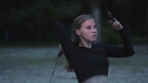 Blond schattig zelfverzekerd vrouw het uitvoeren van een show met vlam staande in het bos of Park. Bekwame vuurshow kunstenaar toont beheersing van de beweging van vuur in de avond — Stockvideo