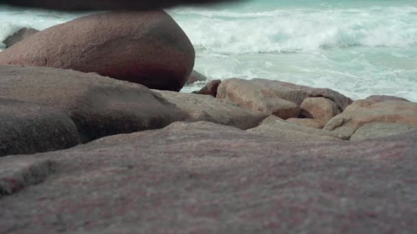 Seychelles. L'île Praslin. Eau propre sur la plage de sable et de grandes pierres sur le sable sur le fond. Humain jetant des fruits et il roule vers le bas. Tourisme, détente, vacances, concept de voyage — Video