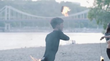 Portre ince adam ağaçların önünde nehir kıyısında ayakta yangın fanı ile bir gösteri yapıyor. Ustaca fireshow sanatçı akşam yangın hayranları ile dans. Yavaş hareket