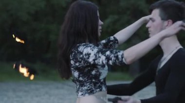 Siyah giysiler ve çekici kadın genç ince adam alev açık havada gösterisi gerçekleştirmek. Ustaca fireshow sanatçılar hokkabazlık ve yangın ayakta yakın hareket ustalığını gösteren. Yavaş hareket